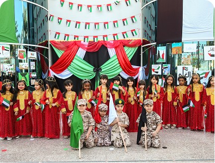 Students in cultural dress standing on a decorated stage